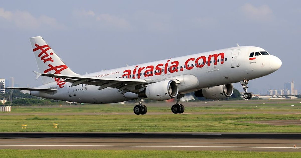 AirAsia Airbus A320 captured taking off from a busy airport runway on a clear day.
