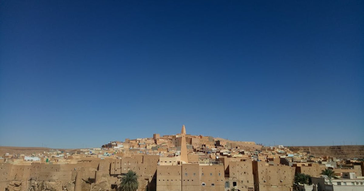 Wide-angle shot of Ghardaïa's traditional architecture under a clear blue sky.