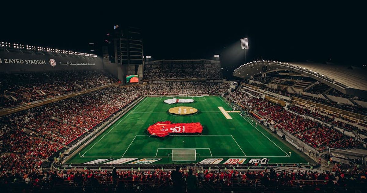 Aerial view of a lively football match at Zayed Stadium, showcasing fans and vibrant atmosphere.