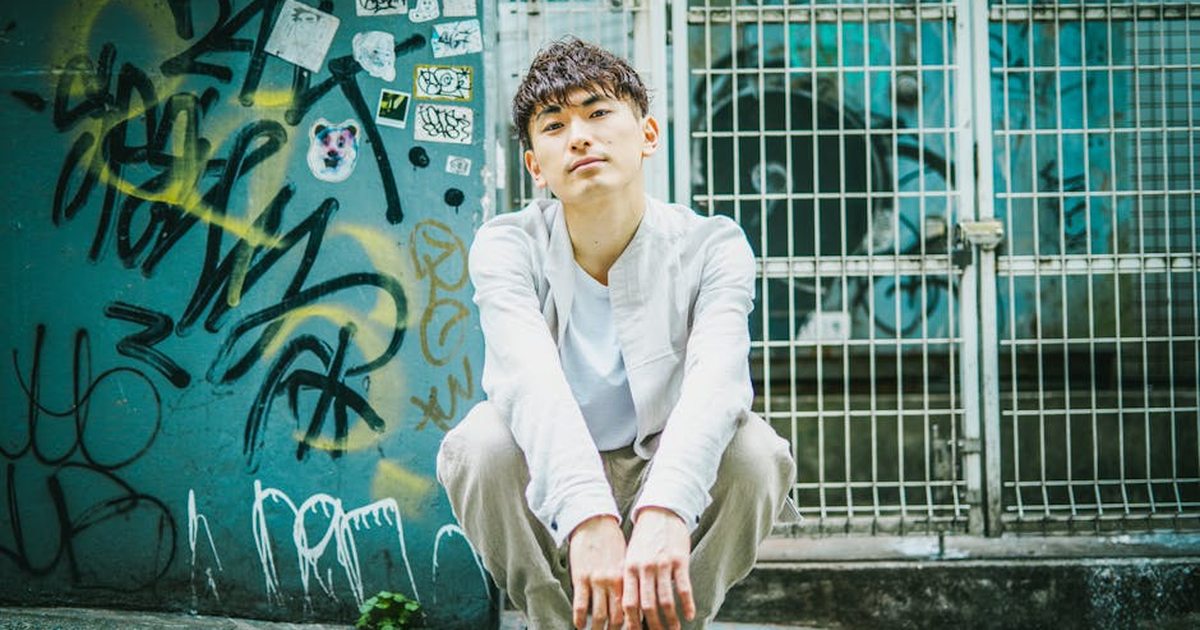 Teenager posing in front of vibrant graffiti, conveying urban street vibe.