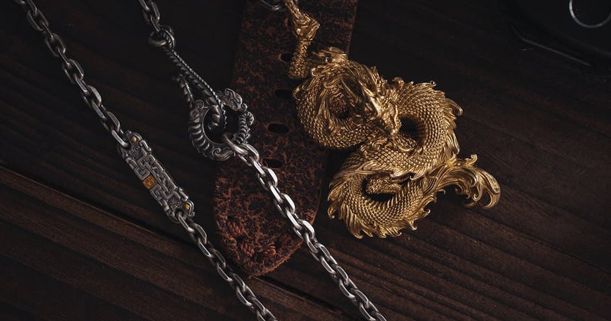 Close-up of a detailed golden dragon pendant on a wooden desk.