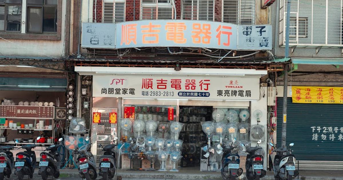 Vintage Taipei storefront with electronics display and parked scooters, showcasing urban culture.