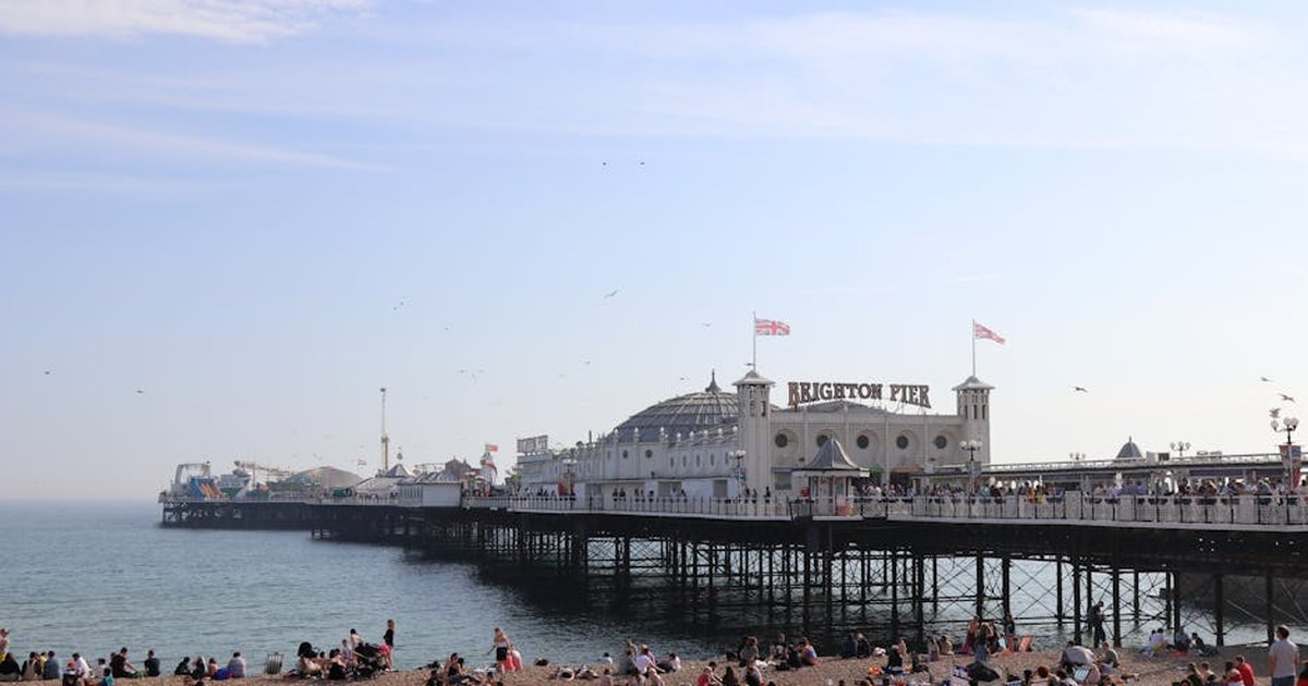 A lively scene of Brighton Pier in England with people enjoying the sunny beach.