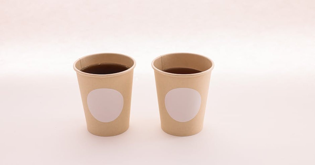 Two paper cups with coffee on a neutral backdrop, perfect for business branding mockups.