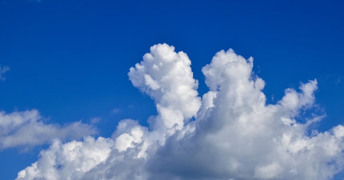 Fluffy cumulus clouds set against a vivid azure blue sky, conveying serenity and calm.