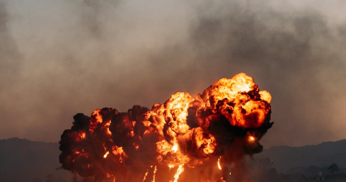 A powerful explosion with intense flames and smoke in an open field during dusk, creating a dramatic scene.