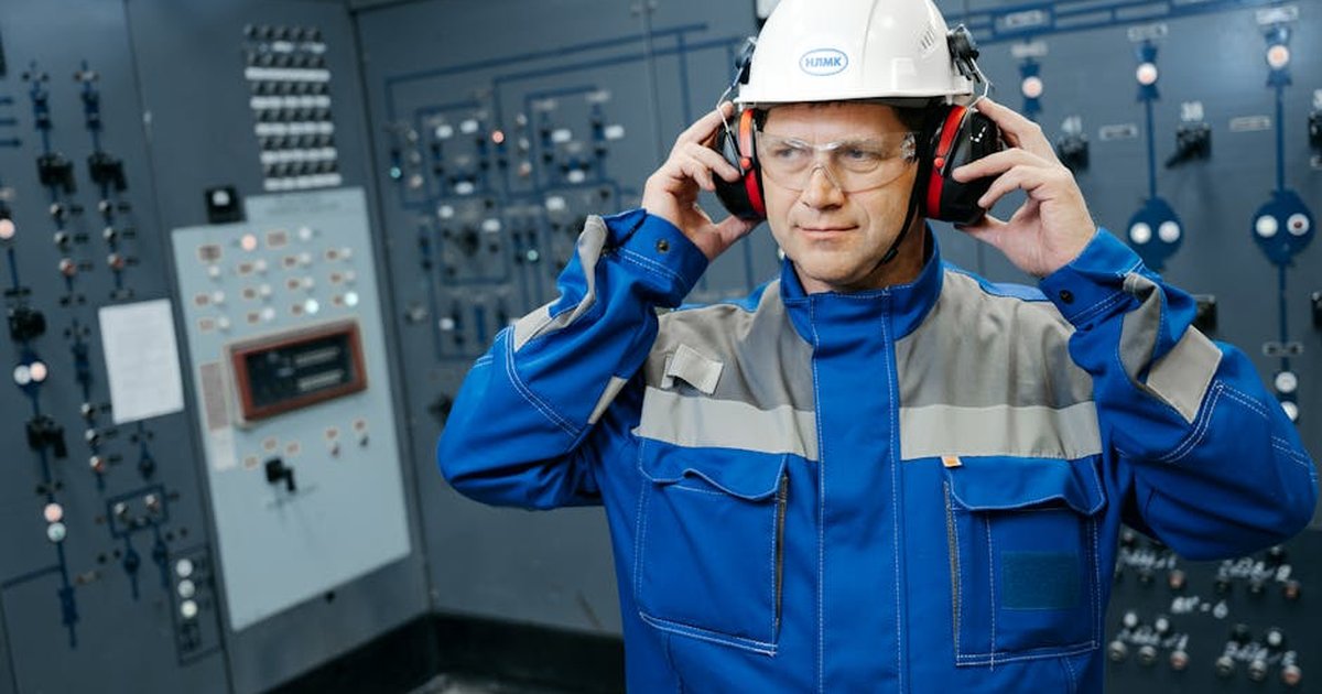Engineer wearing protective gear in a control room, emphasizing safety and technology.