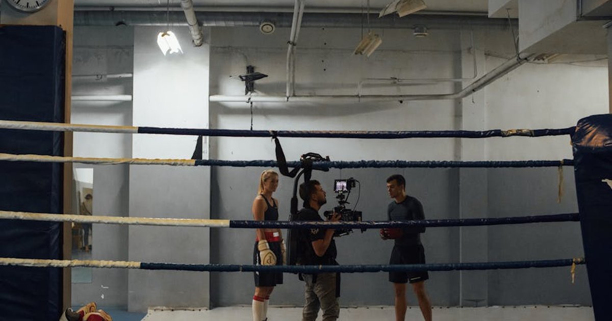 Boxing training scene in an industrial gym with athletes and a videographer capturing the action.