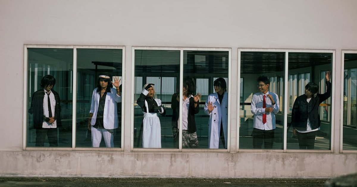 Group of young adults in diverse outfits seen through large windows in an urban setting.