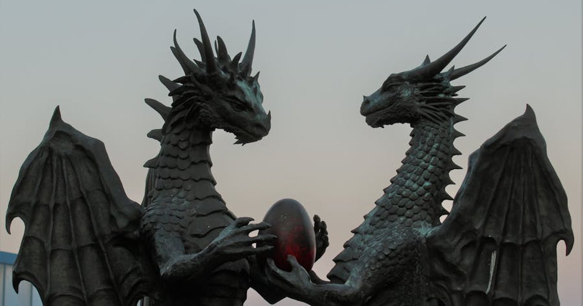 Two impressive dragon sculptures holding an enigmatic egg against a twilight sky, symbolizing fantasy and myth.