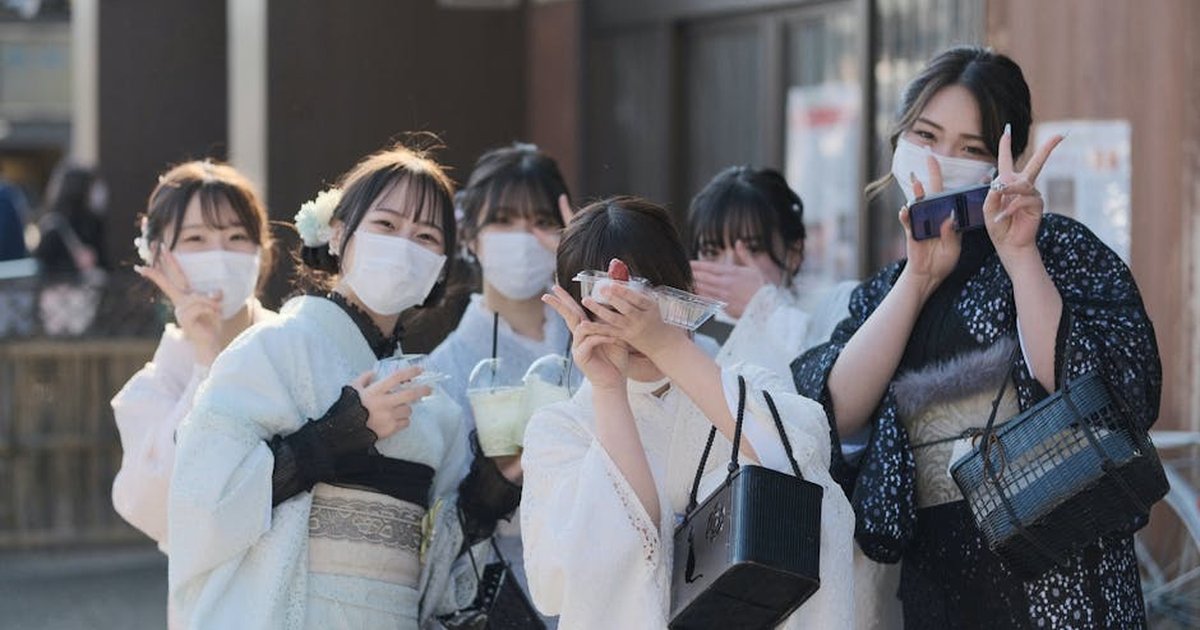 Group of women in traditional yukatas and face masks posing for a photo outdoors.