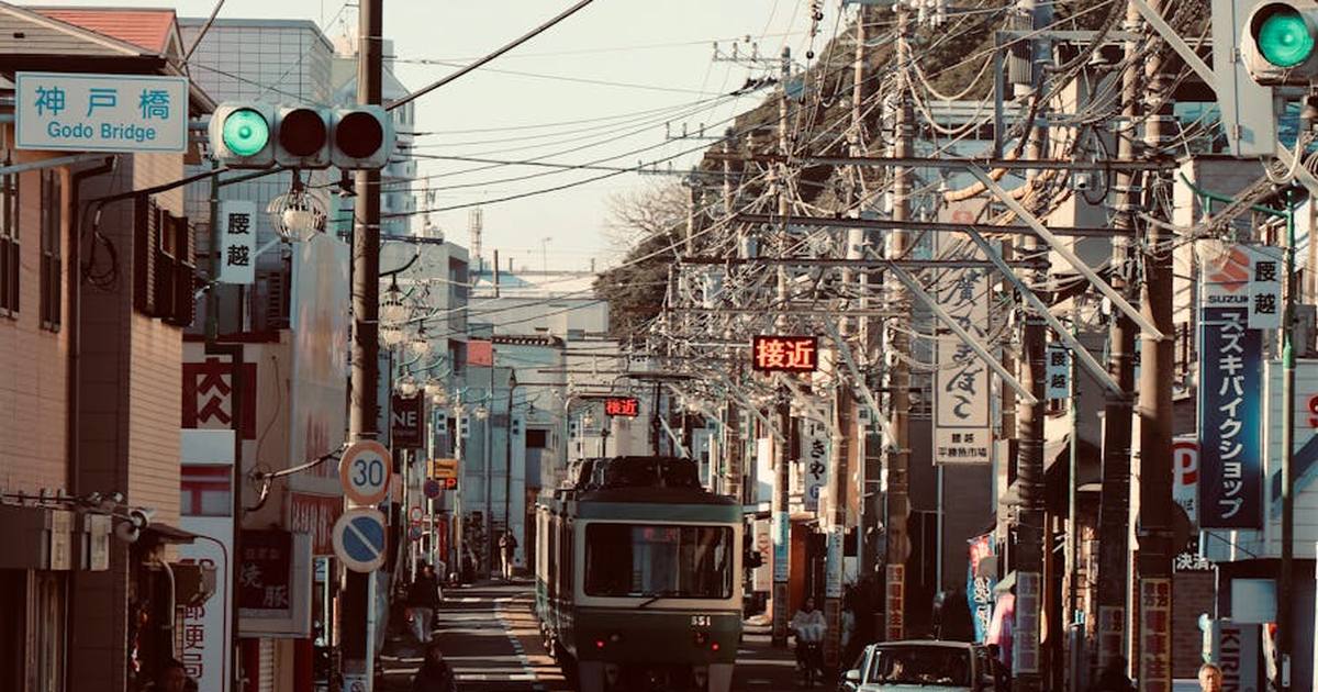Streetcar traveling through a busy street in Kamakura, showcasing Japanese urban life and architecture.