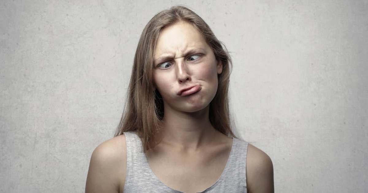 A woman with long hair making a silly expression, adding humor to an otherwise plain gray background.
