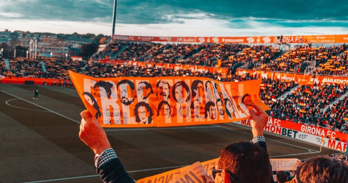 Energetic crowd at Girona FC stadium holding a vibrant banner during a football match.