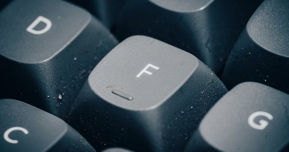 Detailed close-up of dusty keyboard keys with focus on the letter F.