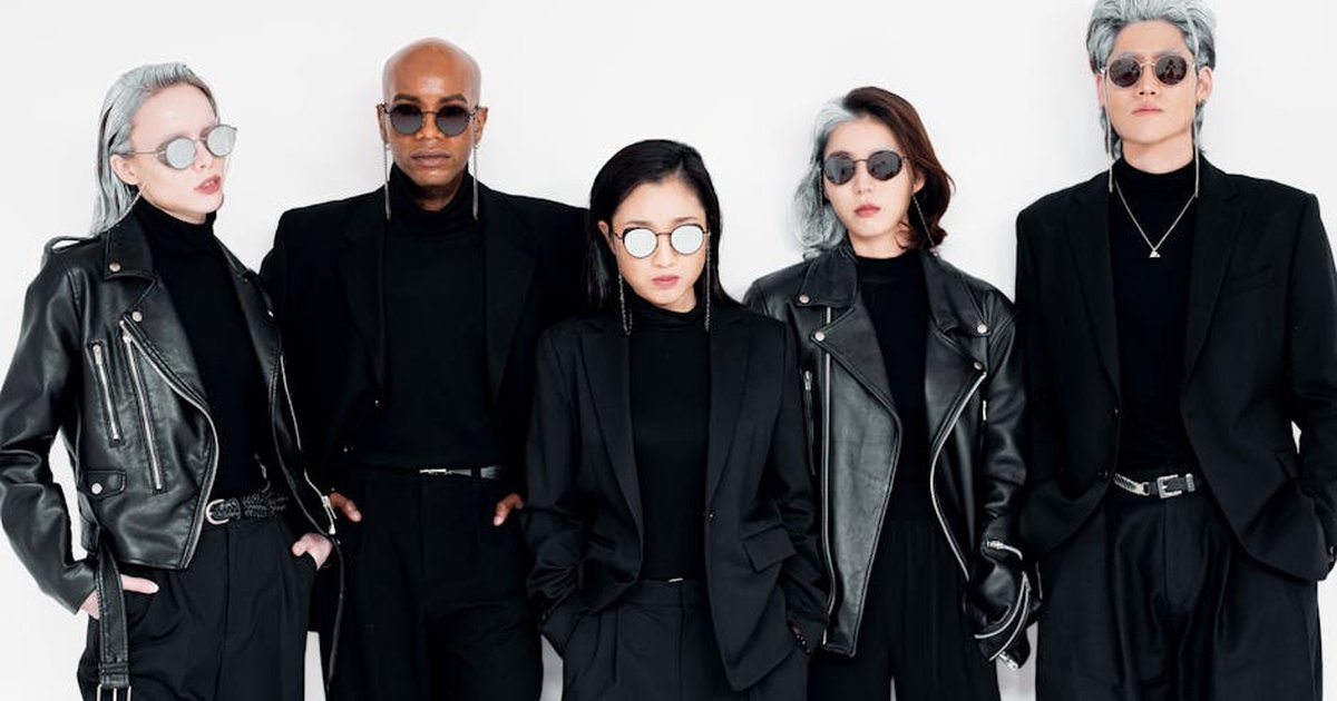 Stylish diverse group in black leather and suits posing against a white background.