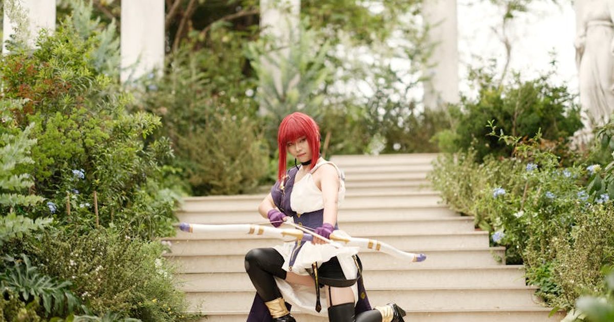 A female cosplayer in archery costume poses on garden temple steps, conveying fantasy allure.