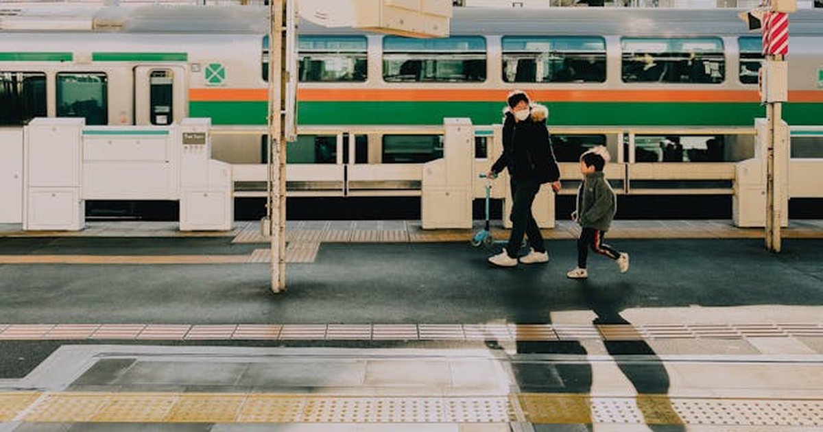 A father and son walk along the platform at a Tokyo train station during the early evening.