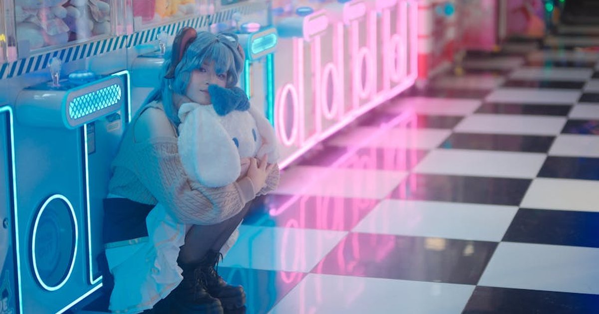 A cosplayer crouches with a plush toy in a vibrantly lit arcade.