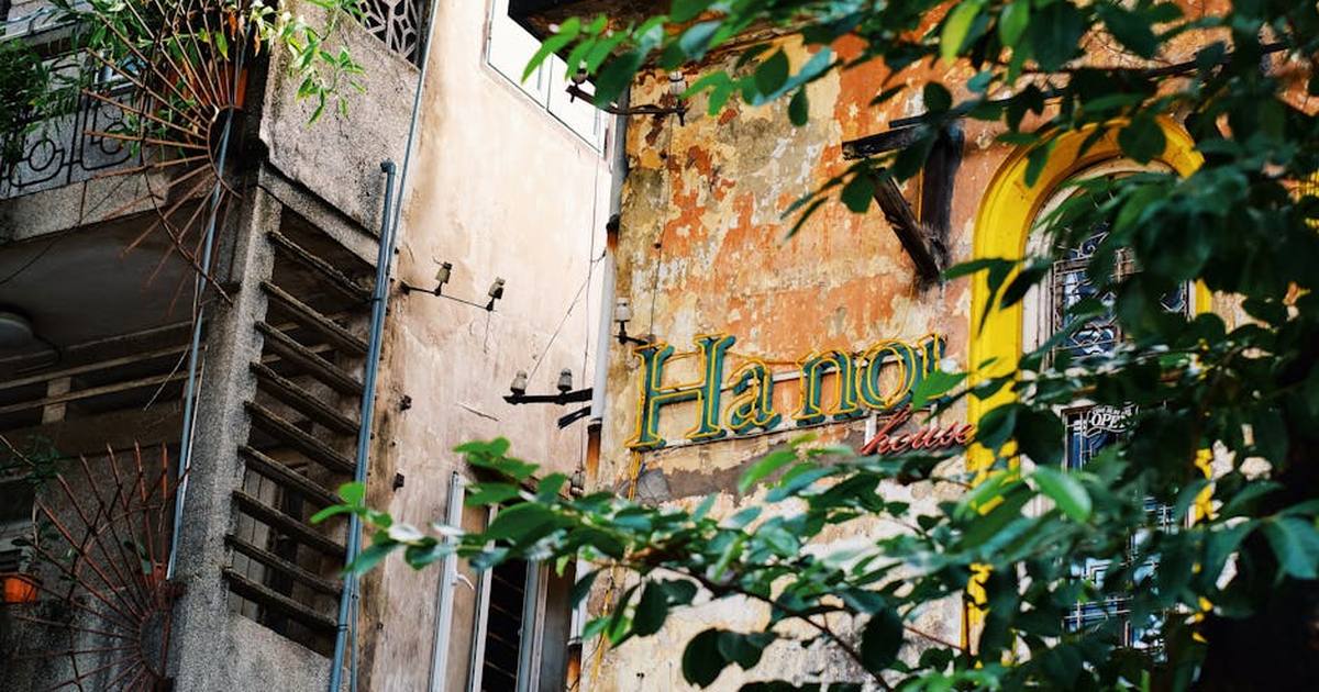 Rustic urban building in Hanoi with lush greenery and distinct signage.