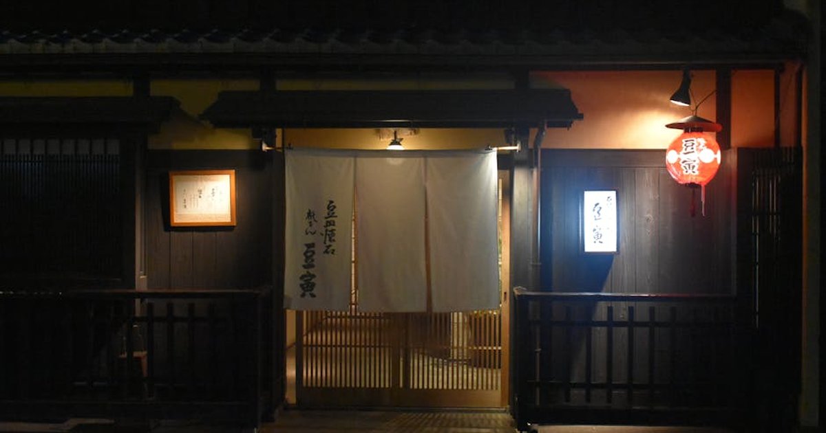 Nighttime view of a traditional Japanese restaurant entrance in Kyoto with lanterns and signage.