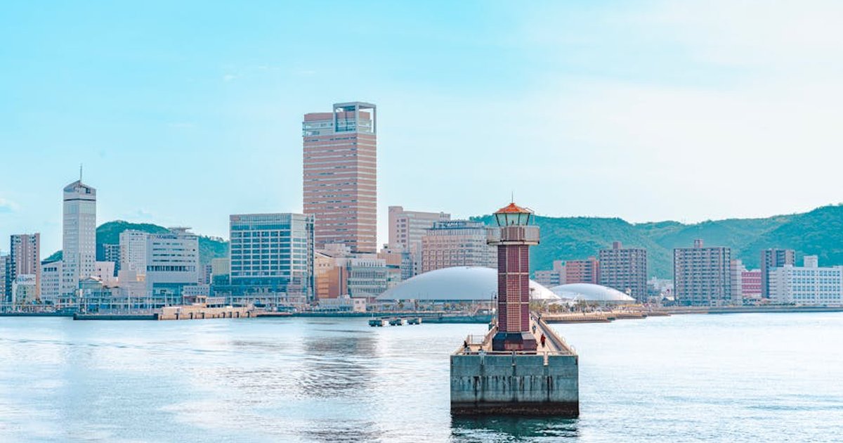 Explore the vibrant skyline of Takamatsu, Japan with a picturesque lighthouse in the foreground.