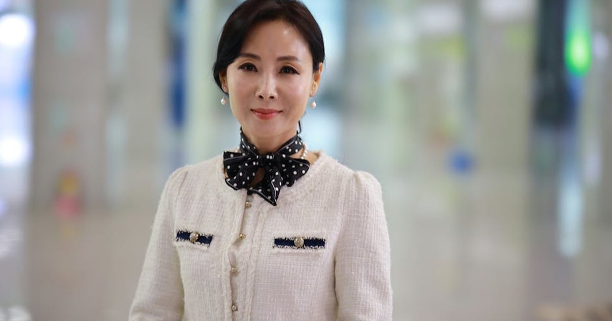 Portrait of an elegant woman with a polka dot scarf, smiling, captured in an indoor setting.