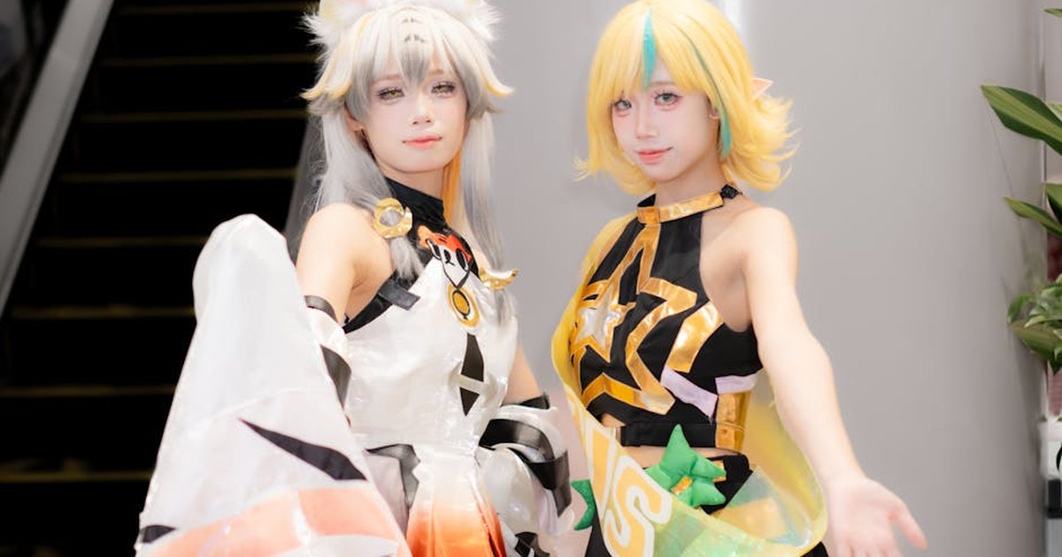 Two cosplayers in colorful costumes posing indoors at a convention.