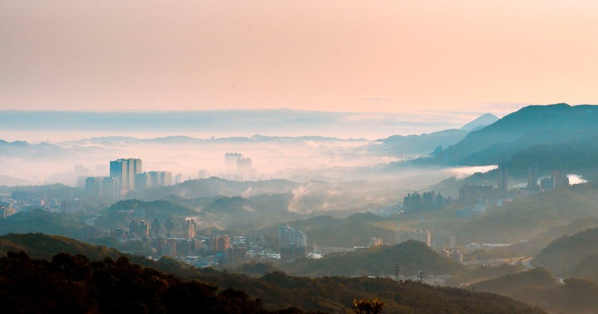 Captivating view of Taipei's skyline surrounded by misty hills during sunrise, showcasing nature and urban harmony.