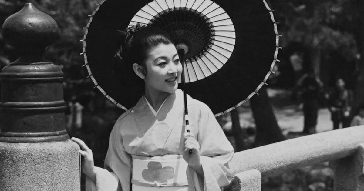 Elegant black and white portrait of a woman in a kimono with a parasol, epitomizing traditional Japanese style.