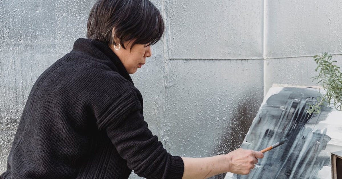 A focused artist painting abstract designs on canvas in a creative studio environment.