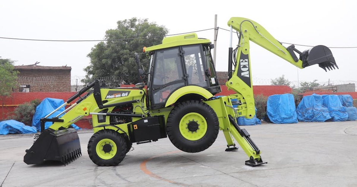 A vibrant ACE Phantom 4x4 backhoe loader is showcased in an outdoor setting in Faridabad, India.