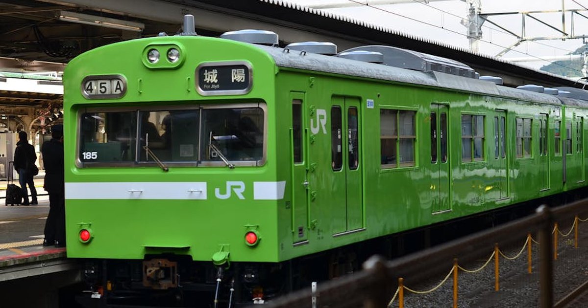 A vivid green JR train waiting at Kyoto station platform, showcasing Japan's efficient railway system.