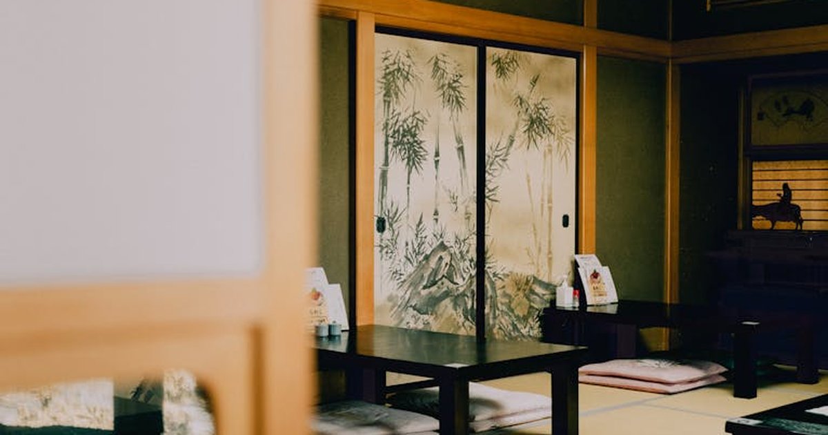 Serene view of a traditional Japanese tatami room with painted sliding doors and low tables.