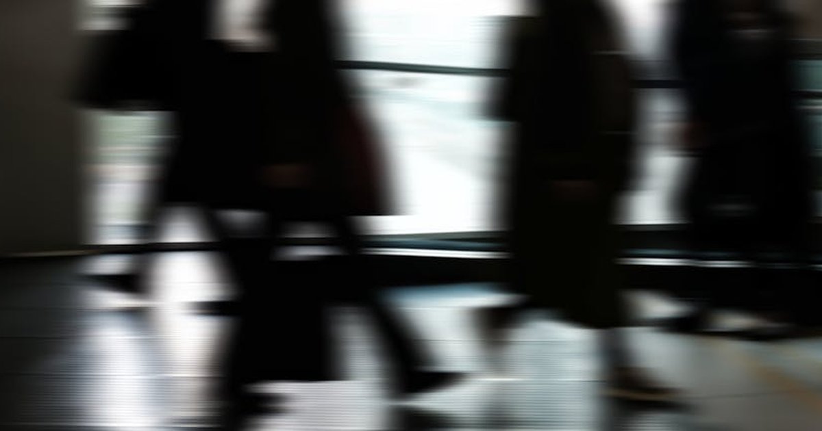 Abstract blurred motion of people walking indoors, depicting urban life and busy routines.