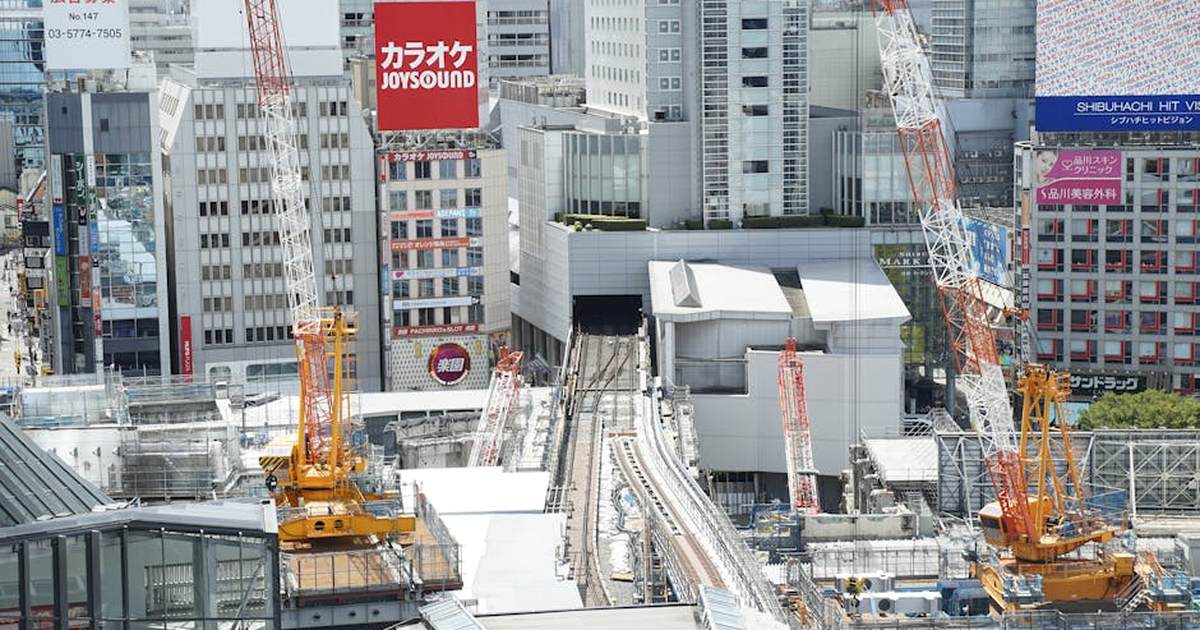 Aerial view of construction cranes in Shibuya, Tokyo with skyscrapers.