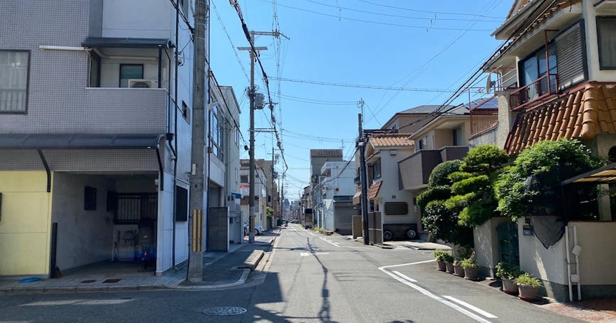 Quiet urban street scene on a sunny day with residential houses and clear blue sky.