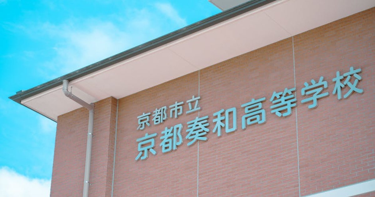 Brick building facade with Japanese text under a clear blue sky in Kyoto, Japan.