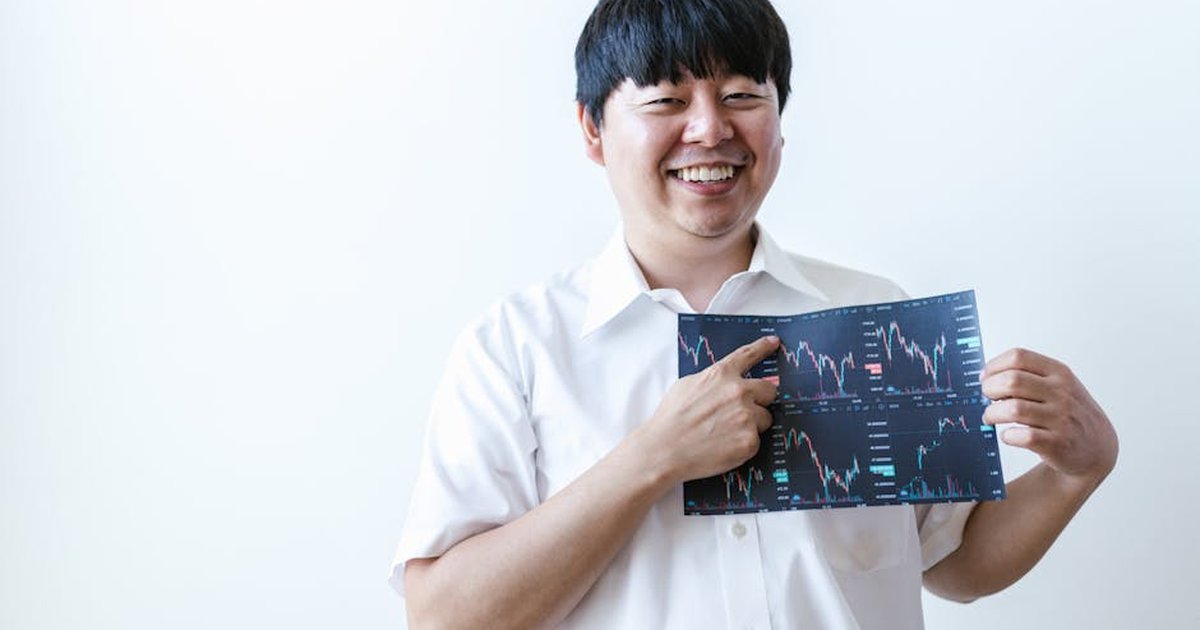 Smiling man presenting cryptocurrency investment chart indoors.