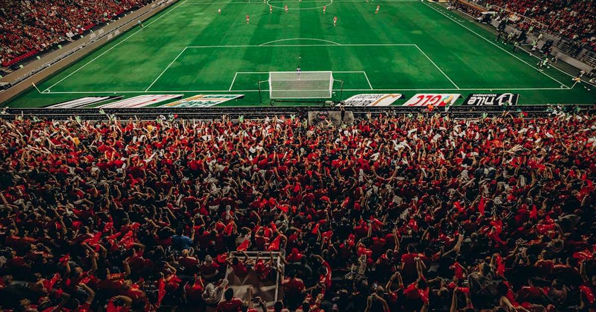 Aerial shot of a lively football match with enthusiastic fans in a packed stadium.
