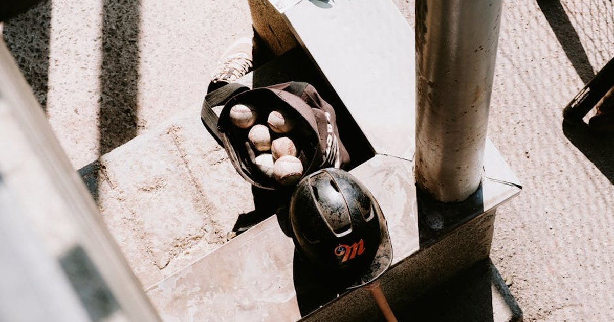 A sunlit scene with a baseball bag, balls, and helmet on urban stairs, perfect for sports imagery.