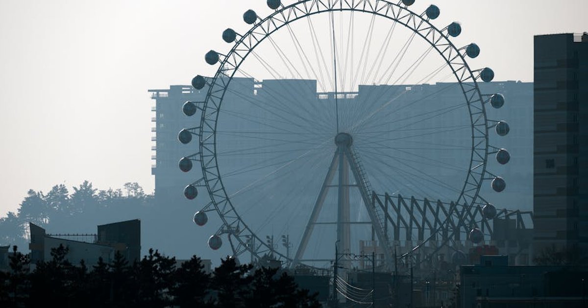 Silhouette of a ferris wheel in Sokcho city, South Korea, against an urban backdrop.