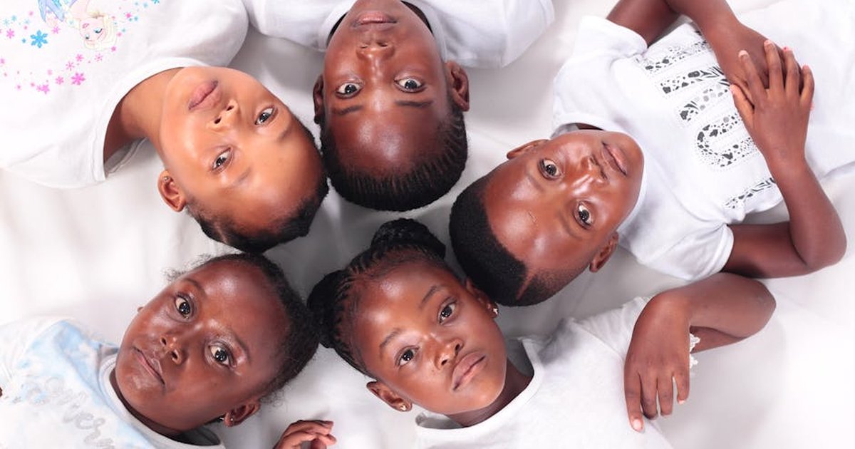A group of smiling children in white shirts lying on a white background, embodying friendship and togetherness.
