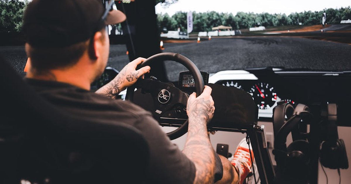 Focused gamer experiencing a detailed driving simulation setup indoors.