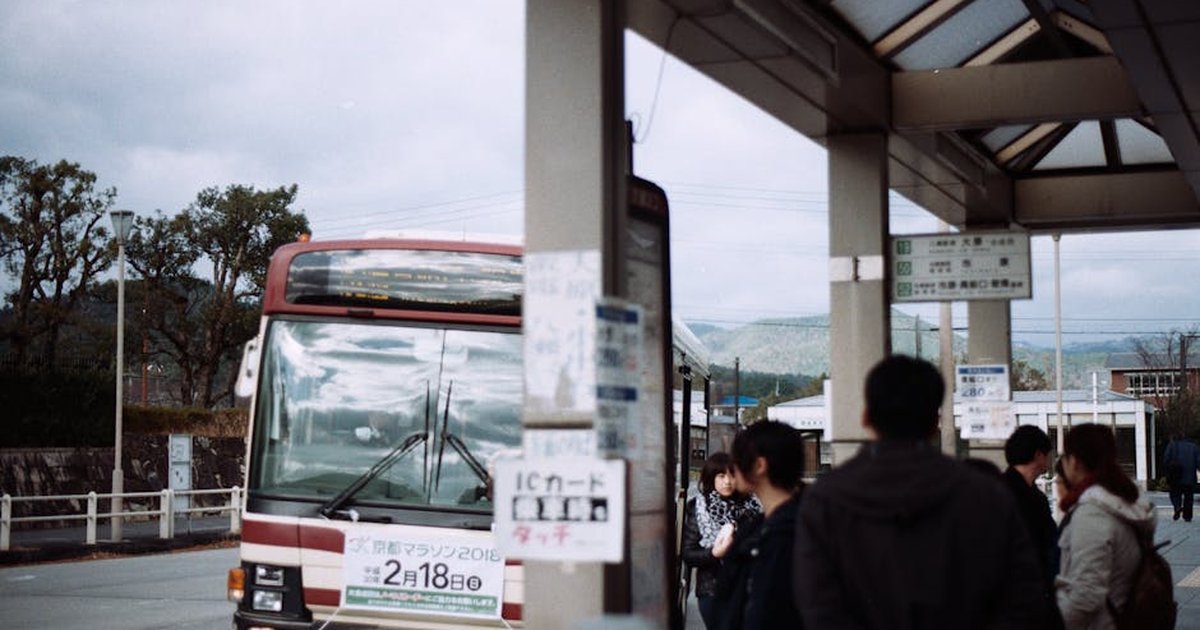 Commuters wait at a bus stop in Nara with scenic background.