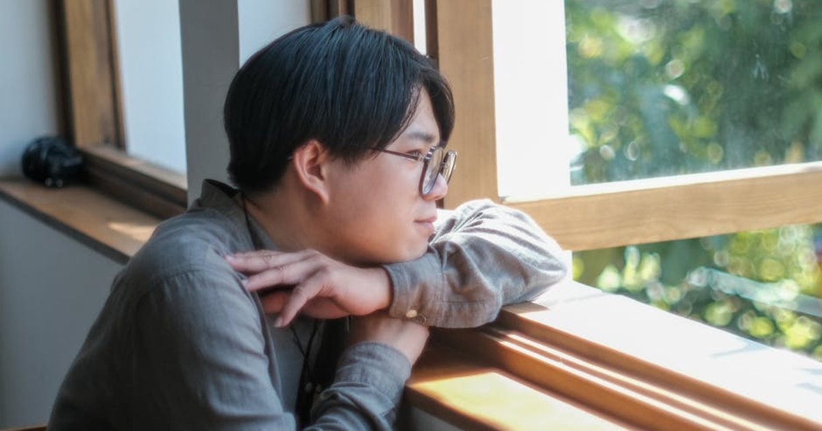 Side profile of a thoughtful man looking out a sunny window in Da Nang, Vietnam.