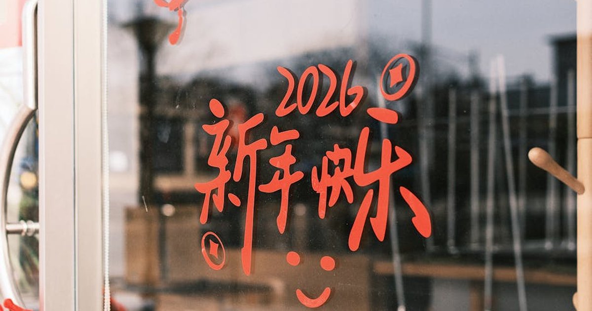 Red Chinese characters with 2026 on a glass door, symbolizing New Year celebrations.