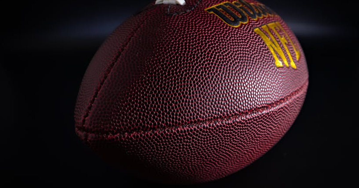 Detailed view of a traditional brown and white American football against a dark backdrop, highlighting texture.