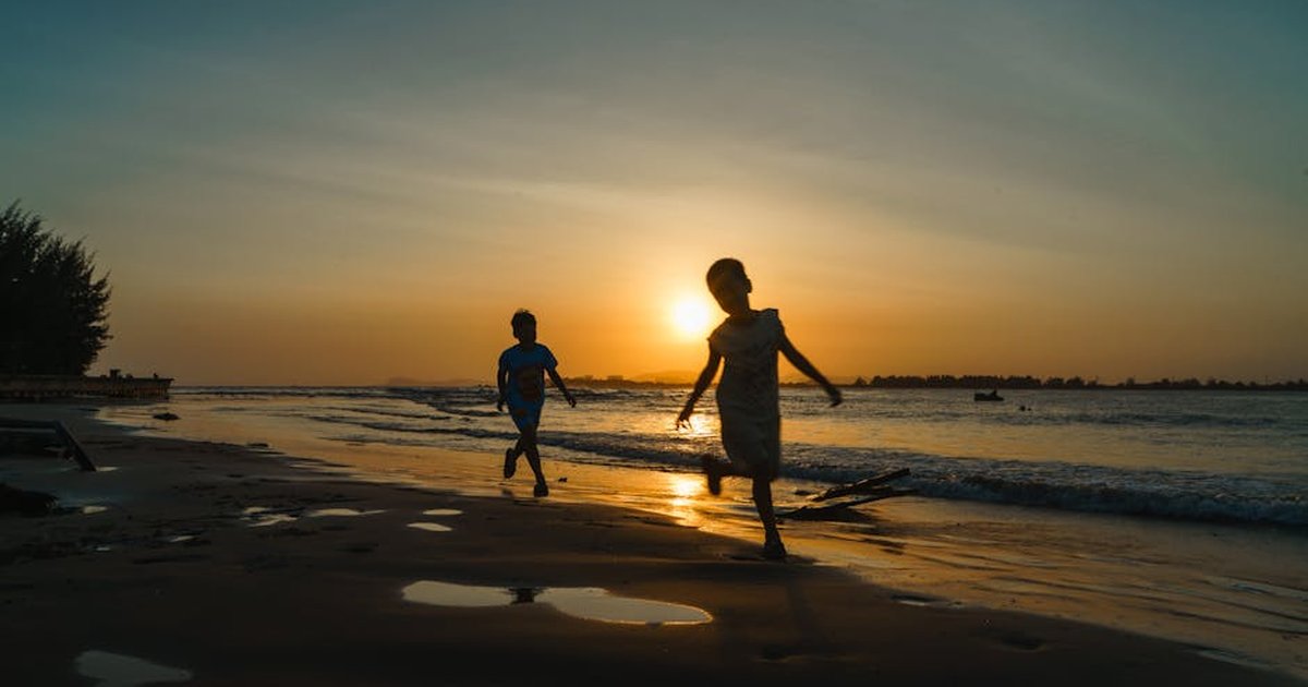 Two children joyfully playing on the beach during a beautiful sunset in Vũng Tàu, Vietnam.