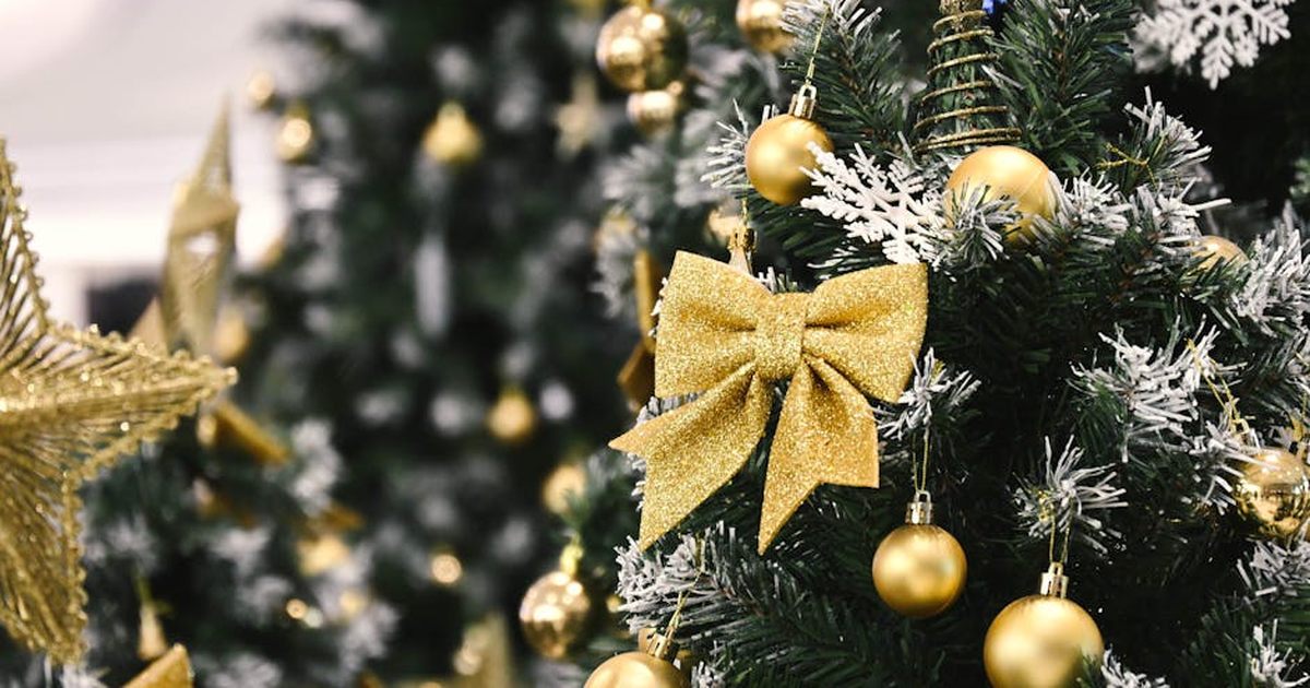 Elegant Christmas tree adorned with gold ornaments and a sparkling bow, capturing the holiday spirit in a festive setting.